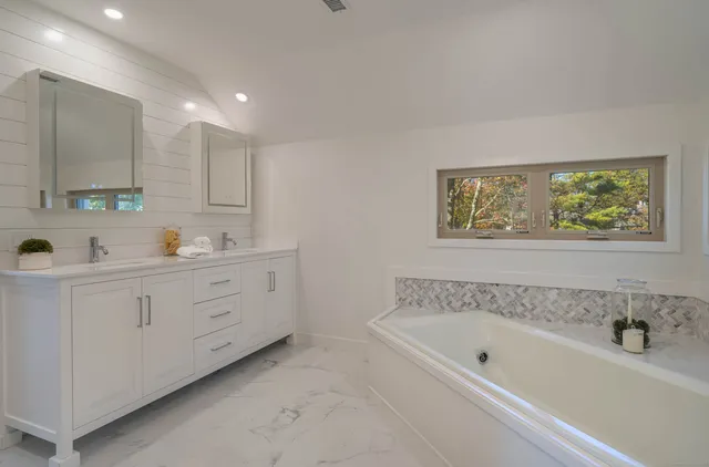 a spacious bathroom with a tub sink and a window