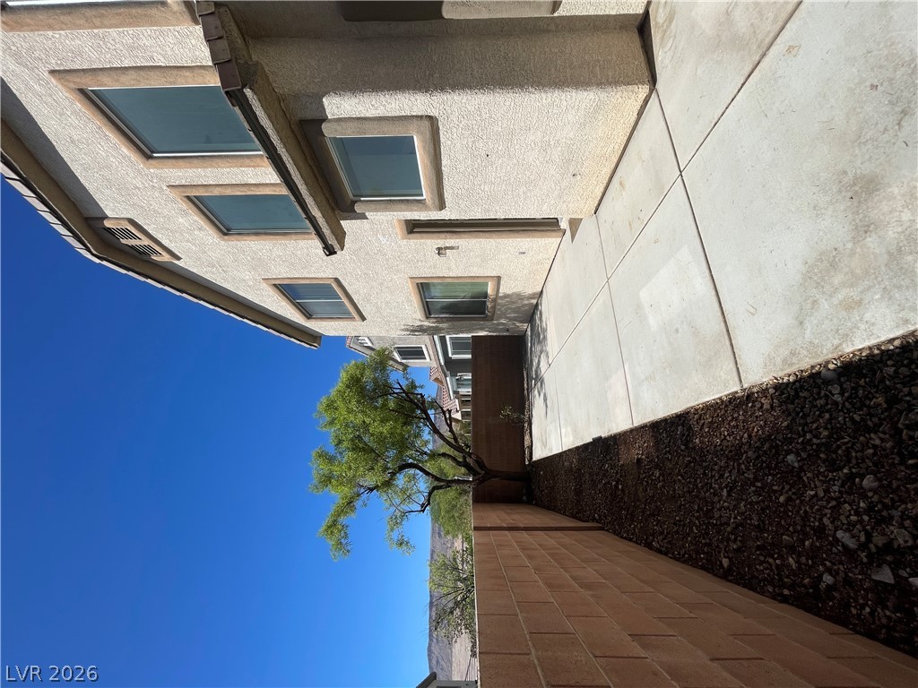 11049 Zarod Road Las Vegas, NV 89135 - Photo 17 of 17 Concrete walkways trace the side of this multi-story stucco home framed by block wall fencing.