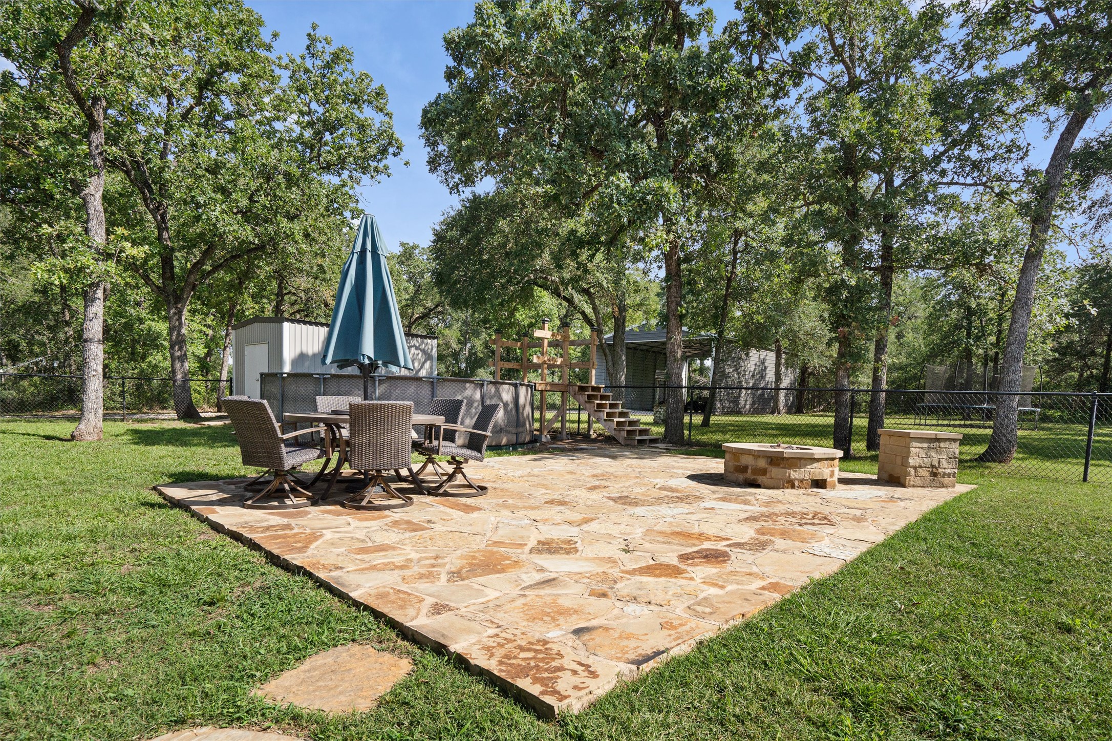 136 Fawn Hollow Elgin, TX 78621 - Photo 34 of 40 Expansive flagstone patio area with a built-in stone fire pit and a stone-clad raised planter