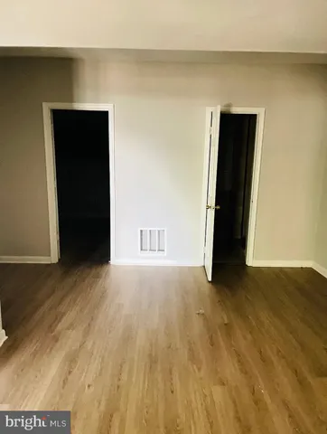 a view of an empty room with wooden floor and closet