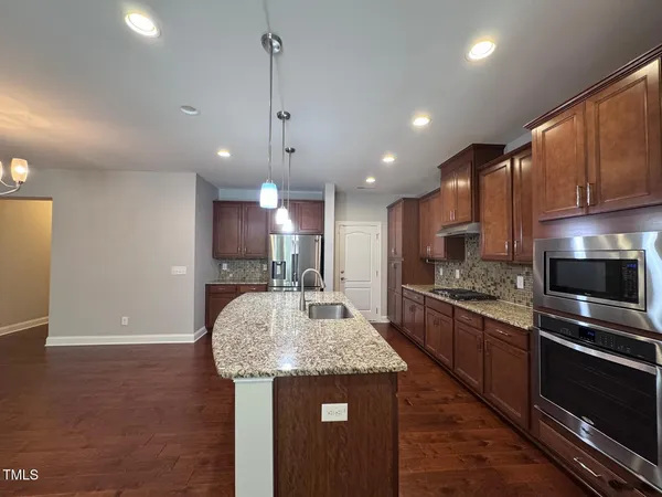 a kitchen with stainless steel appliances granite countertop a sink a stove and a refrigerator