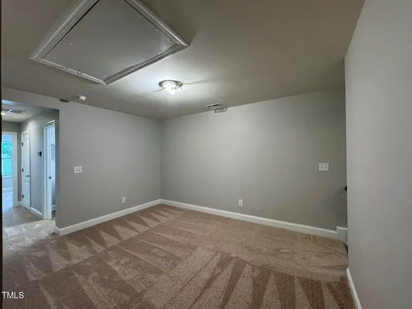 an empty room with a fan & a window