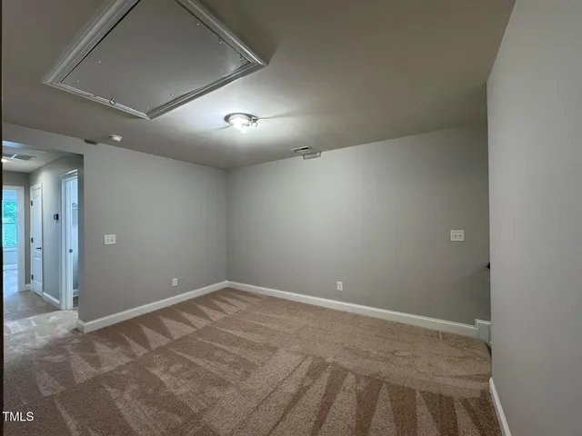 an empty room with a fan & a window