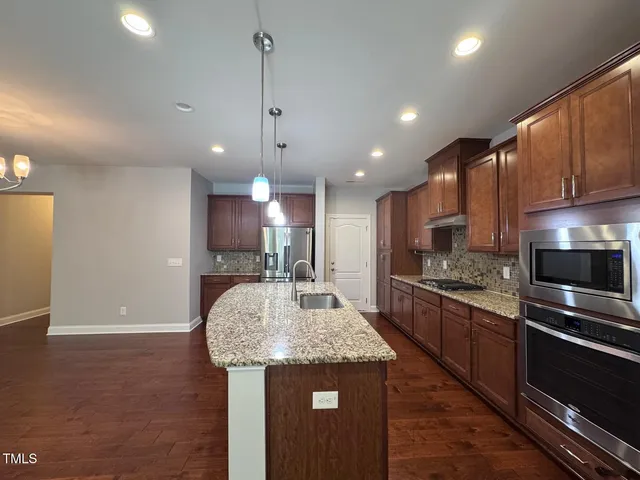 a kitchen with stainless steel appliances granite countertop a sink a stove and a refrigerator