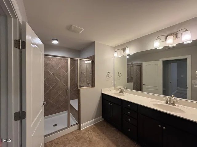 a bathroom with a double vanity sink mirror and shower