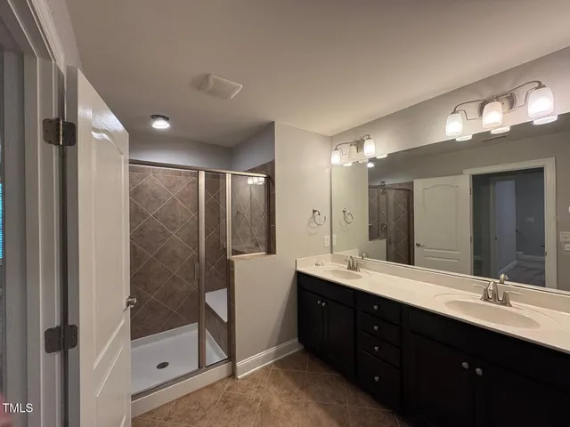 a bathroom with a double vanity sink mirror and shower