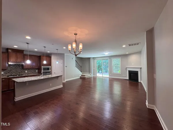an open kitchen with sink and a fireplace with wooden floor