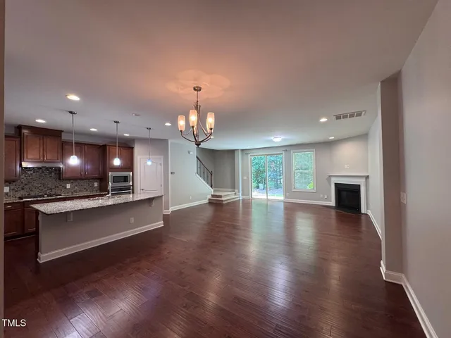 an open kitchen with sink and a fireplace with wooden floor