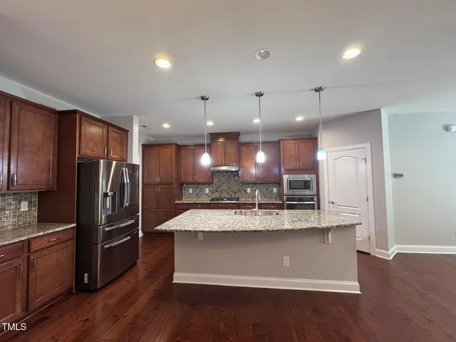 a large kitchen with stainless steel appliances kitchen island a large counter top and wooden floors