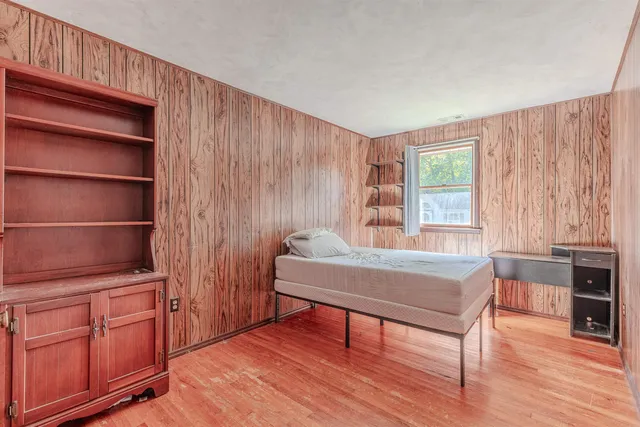 a bedroom with a bed and wooden floor