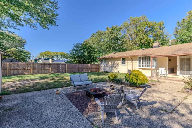 a view of a backyard with table and chairs potted plants and large tree