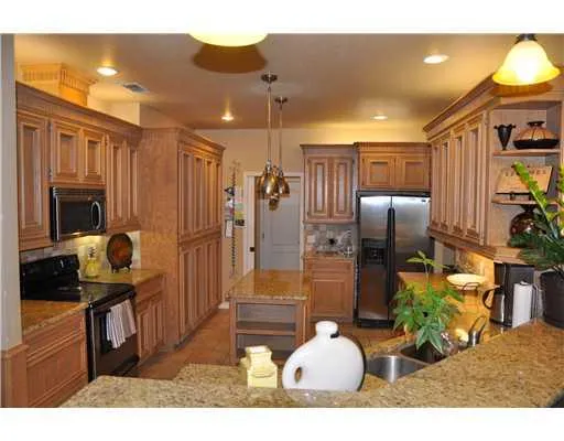 a kitchen with stainless steel appliances kitchen island granite countertop a refrigerator and a stove