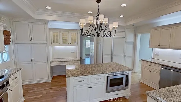 a kitchen with stainless steel appliances granite countertop a refrigerator a stove and a sink with wooden floor