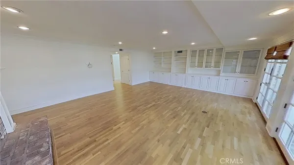 an empty room with wooden floor fireplace and windows