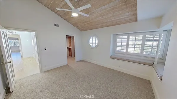 an empty room with windows and chandelier fan