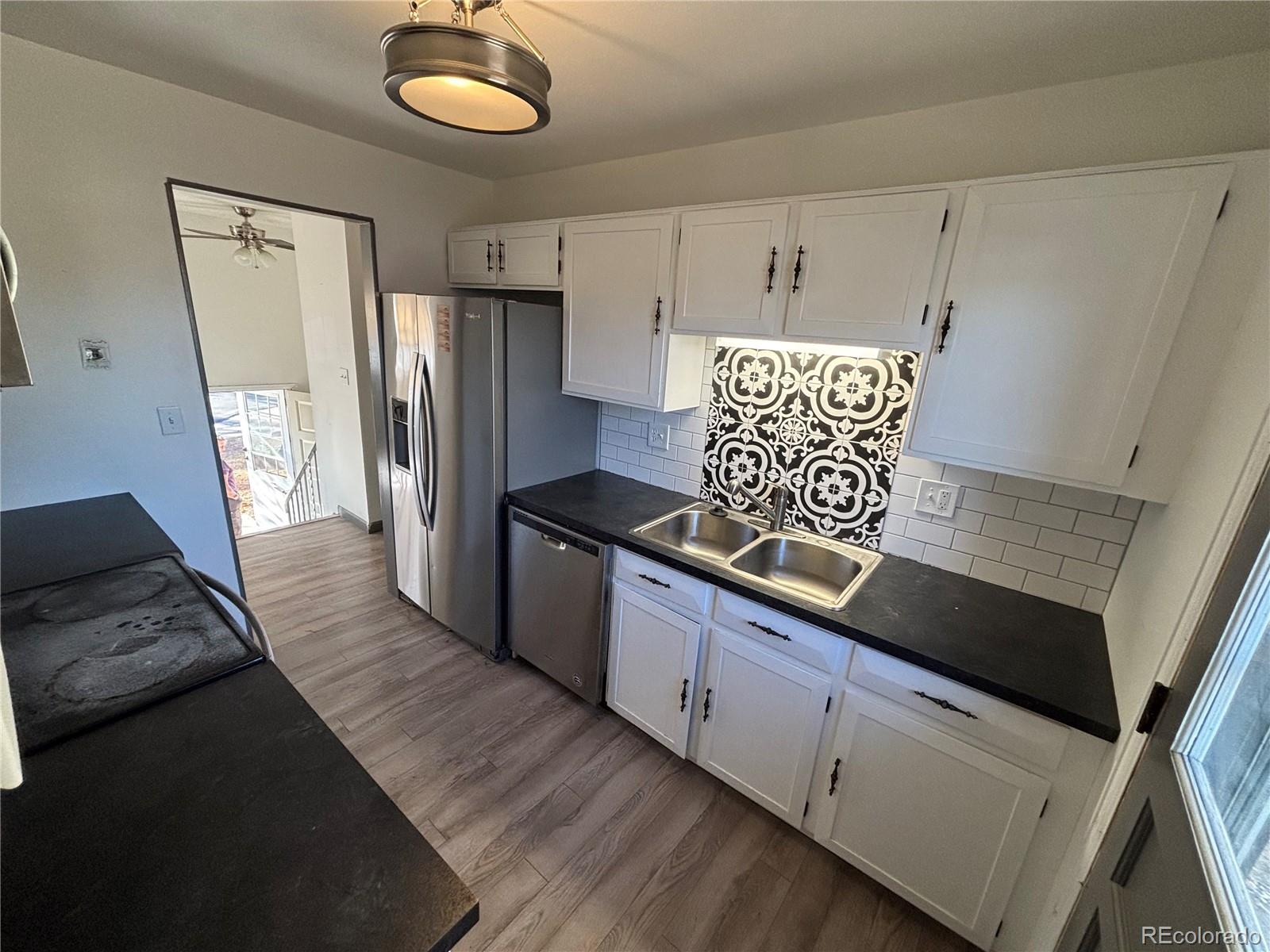 9162 Cody Street Broomfield, CO 80021 - Photo 2 of 29 a kitchen with kitchen island granite countertop a refrigerator and a stove top oven