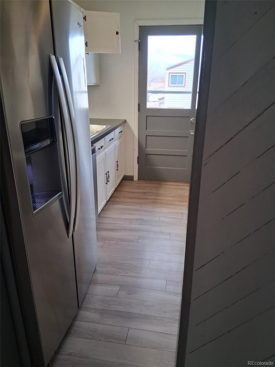 9162 Cody Street Broomfield, CO 80021 - Photo 6 of 29 a kitchen with white cabinets and refrigerator