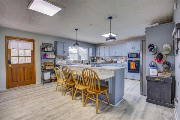 a living room with stainless steel appliances lots of furniture and kitchen view