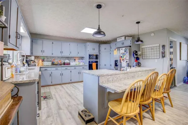 a kitchen with stainless steel appliances granite countertop a dining table chairs sink and cabinets