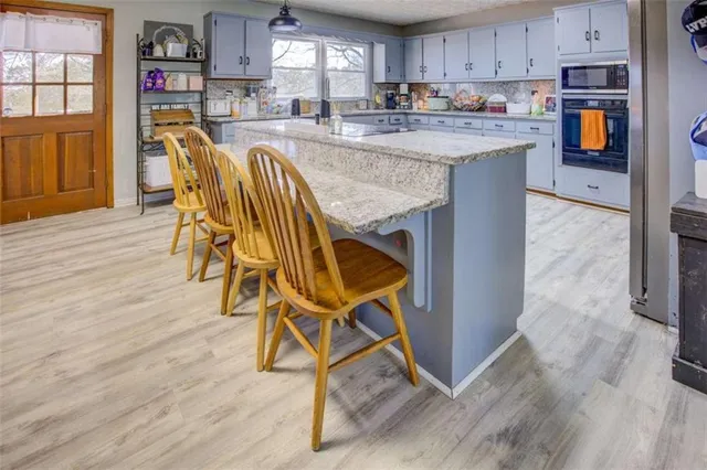 a open kitchen with stainless steel appliances granite countertop a stove top oven a refrigerator a sink and dishwasher with wooden floor