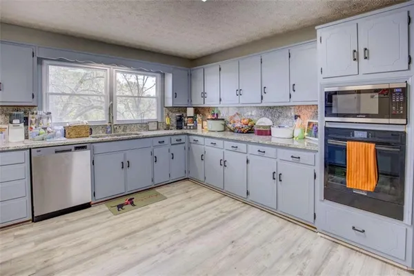 a kitchen with stainless steel appliances granite countertop a stove a sink and white cabinets with wooden floor
