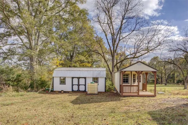 a view of a wooden house with large trees and fence