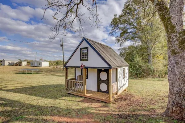 a view of a house with a big yard and large trees