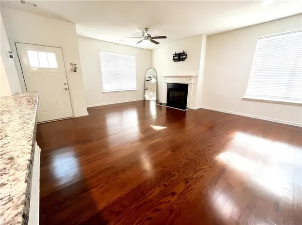 a view of an empty room with wooden floor fireplace and a window