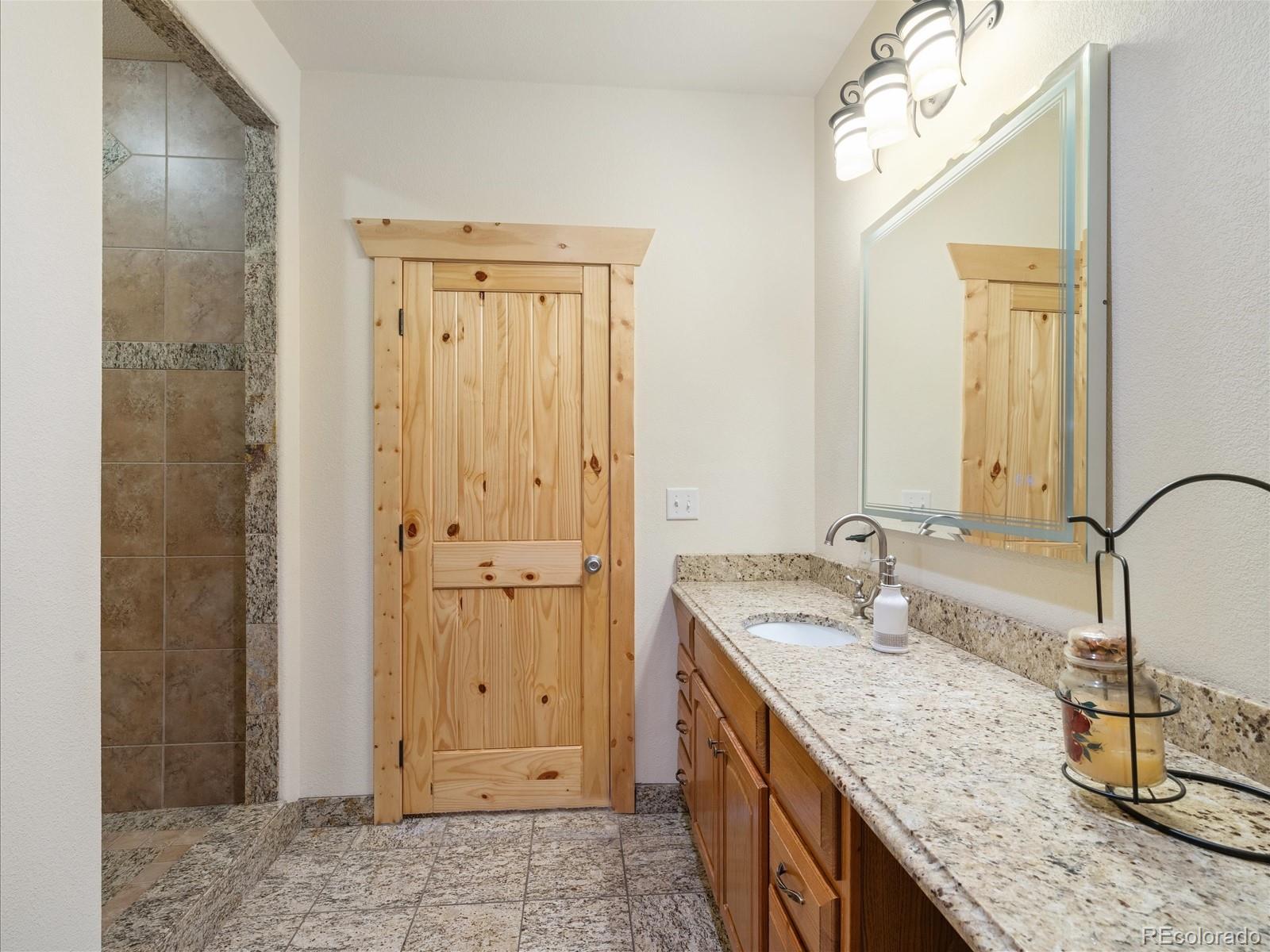479 Dakota Ridge Road Idaho Springs, CO 80452 - Photo 34 of 50 a bathroom with a granite countertop sink and a mirror