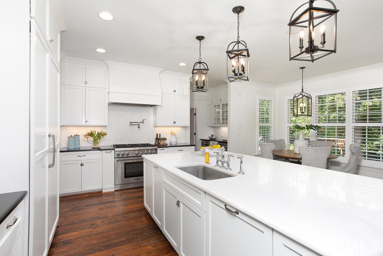 902 Shelley Road Raleigh, NC 27609 - Photo 9 of 45 a kitchen with a sink a stove a refrigerator and white cabinets