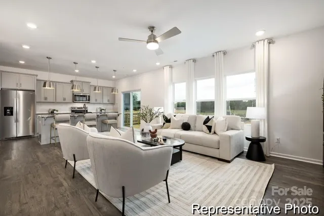 a living room with furniture kitchen area and a large window