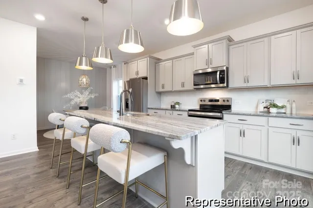 a kitchen with stainless steel appliances a dining table chairs a sink and a refrigerator