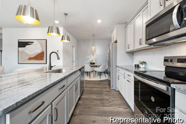 a kitchen with stainless steel appliances granite countertop a stove a sink and a microwave
