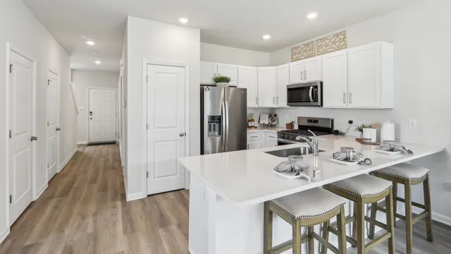 a kitchen with stainless steel appliances kitchen island granite countertop a refrigerator and a sink