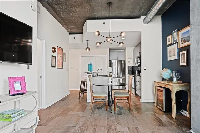 a kitchen with stainless steel appliances granite countertop a stove a refrigerator a dining table and chairs with wooden floor