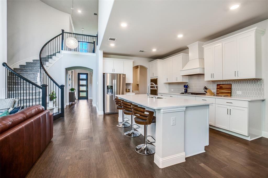 311 Suncrest Way Sunnyvale, TX 75182 - Photo 15 of 40 a kitchen with granite countertop a stove top oven a sink a refrigerator and white cabinets with wooden floor