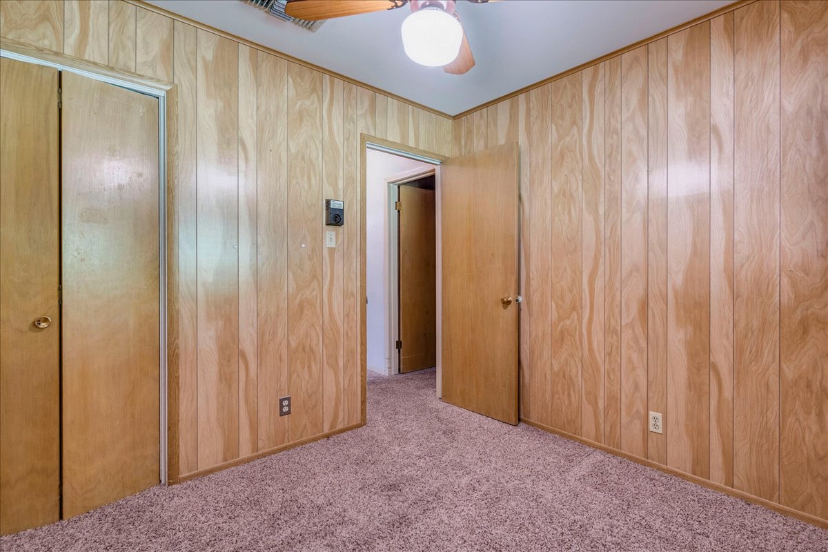 6626 Isabelle Drive Austin, TX 78752 - Photo 20 of 27 Bedroom featuring wood-paneled walls and a ceiling fan with integrated lighting