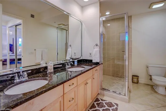 a bathroom with a granite countertop double vanity sink mirror and toilet