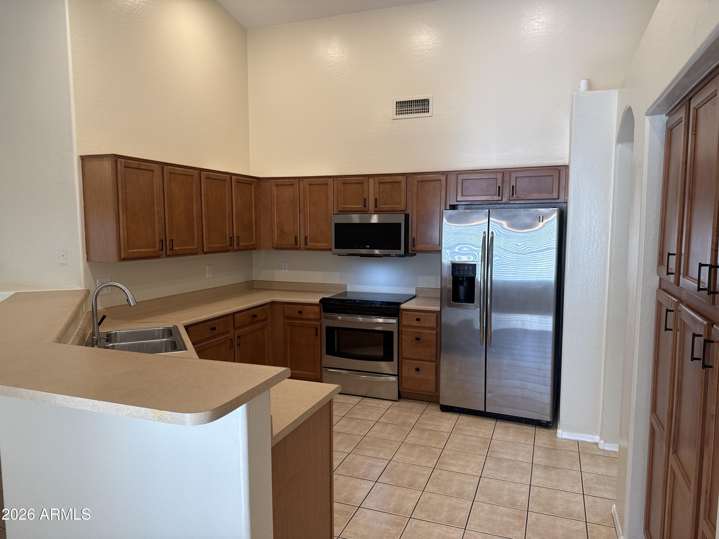 9630 West Reno View Drive Peoria, AZ 85345 - Photo 5 of 21 a kitchen with a sink a microwave a refrigerator and cabinets