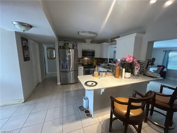 a kitchen with stainless steel appliances kitchen island granite countertop a table chairs and a refrigerator