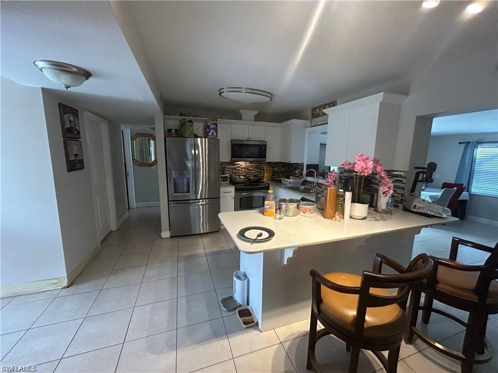 4920 Cortez Circle Naples, FL 34112 - Photo 2 of 7 a kitchen with stainless steel appliances kitchen island granite countertop a table chairs and a refrigerator