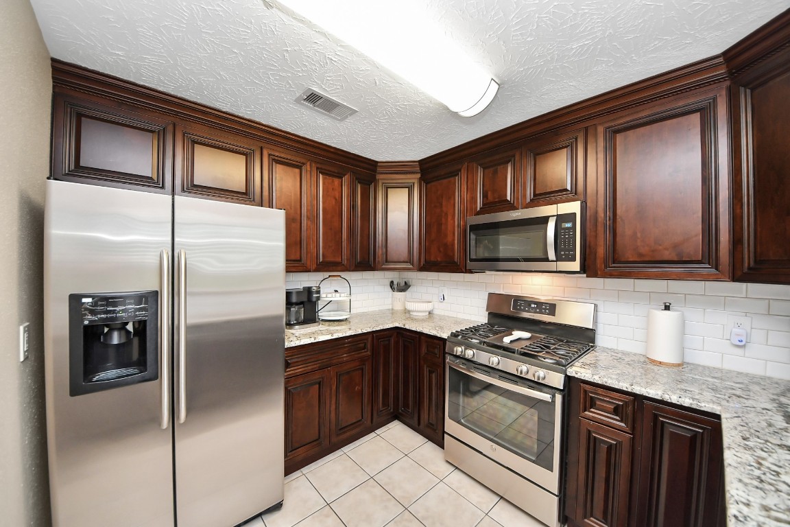 9634 Thistle Trail Drive Houston, TX 77070 - Photo 6 of 22 a kitchen with stainless steel appliances granite countertop a refrigerator stove and sink