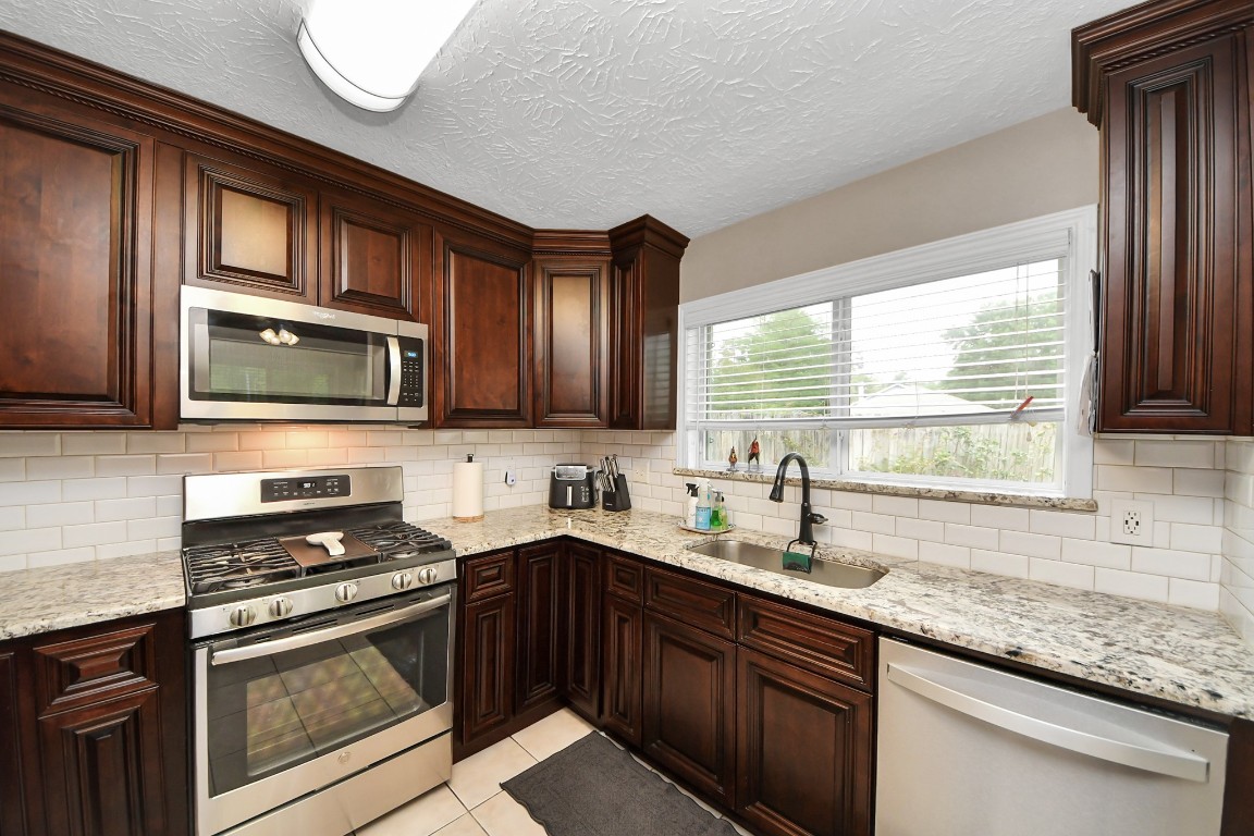 9634 Thistle Trail Drive Houston, TX 77070 - Photo 7 of 22 a kitchen with stainless steel appliances granite countertop a sink stove microwave and cabinets