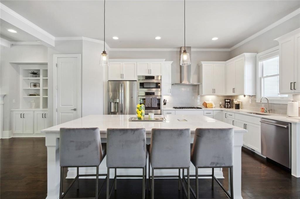 692 Drewry Street Northeast Atlanta, GA 30306 - Photo 9 of 25 a kitchen with kitchen island a dining table chairs and white cabinets