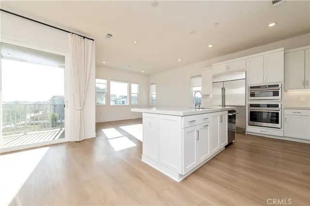 a kitchen with stainless steel appliances a white cabinets and wooden floors