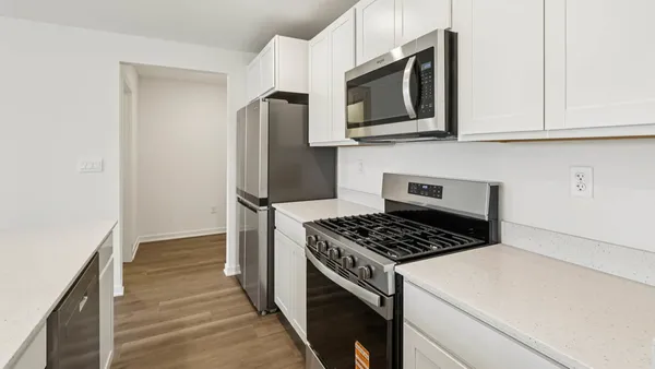 a kitchen with stainless steel appliances white cabinets and a stove top oven