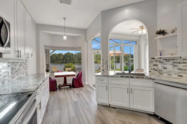 a large kitchen with stainless steel appliances stove a sink and dishwasher a refrigerator with wooden floor