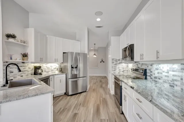 a kitchen with granite countertop a sink stainless steel appliances and cabinets