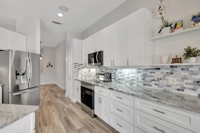 a kitchen with granite countertop a refrigerator and a sink dishwasher with wooden floor