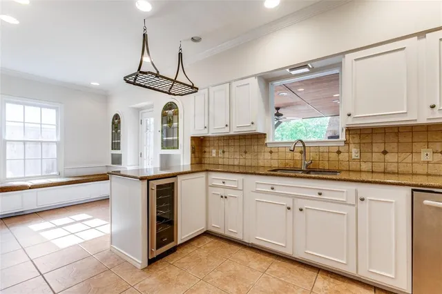 a kitchen with granite countertop white cabinets white appliances a sink and a window